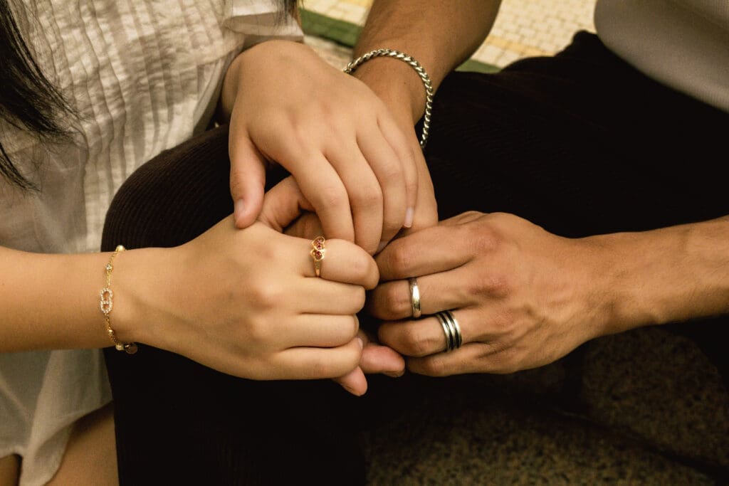 Close-up engagement detail photo of a couple holding hands, showing rings and delicate jewelry during a Houston anniversary photo session.