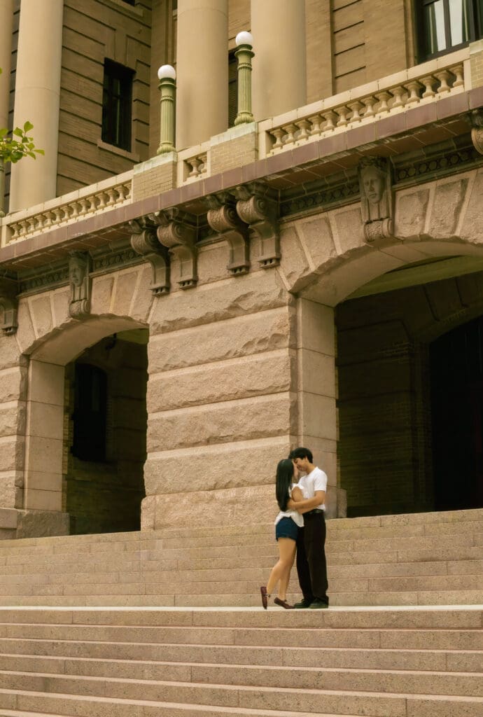 Couple embracing on the steps of the 1910 Courthouse Building during an editorial downtown Houston anniversary session.