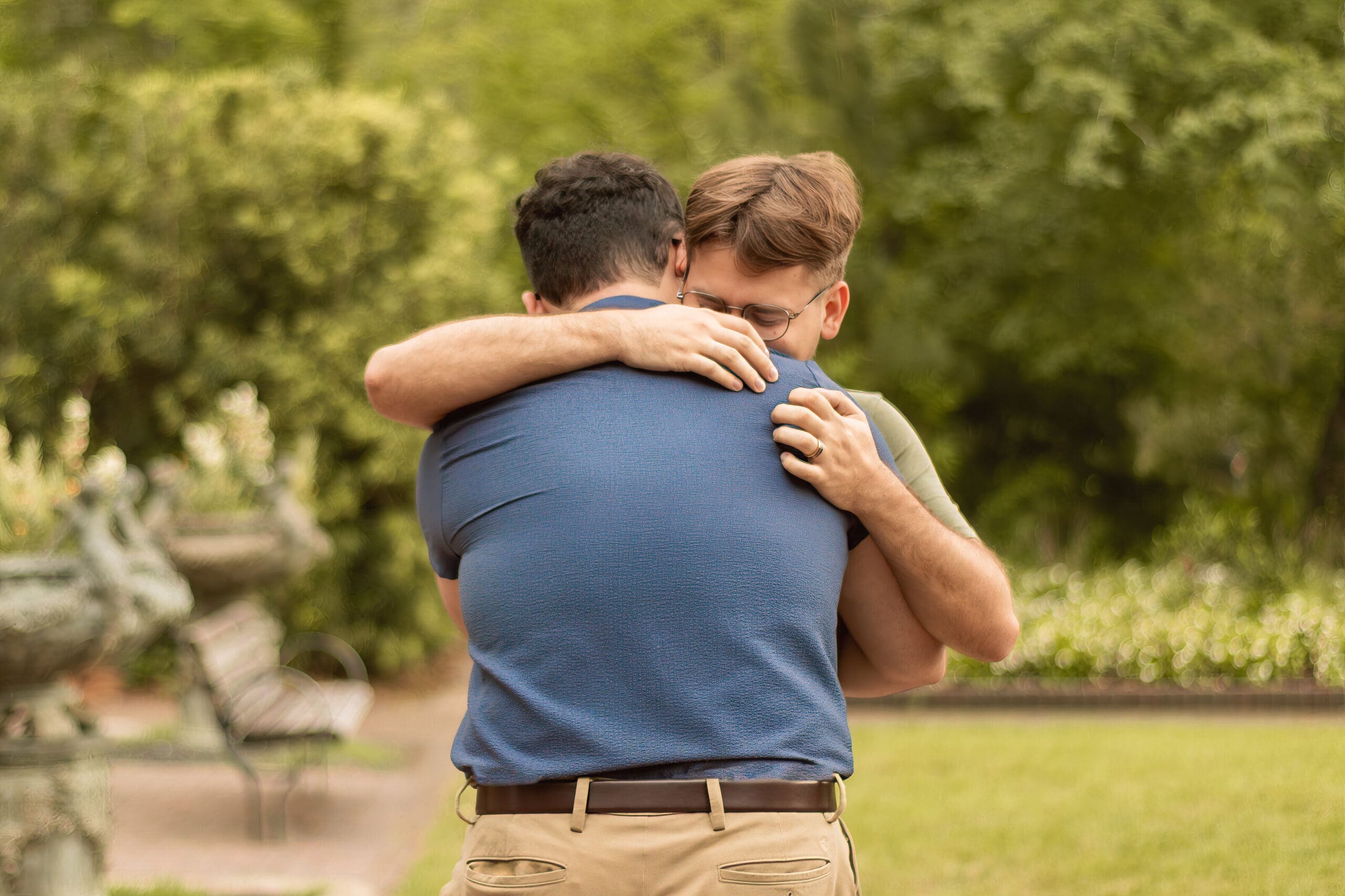 Couple hugging during an engagement session at Mercer Botanic Gardens in Houston, Texas, with garden pathways, greenery, and natural light creating a romantic portrait.