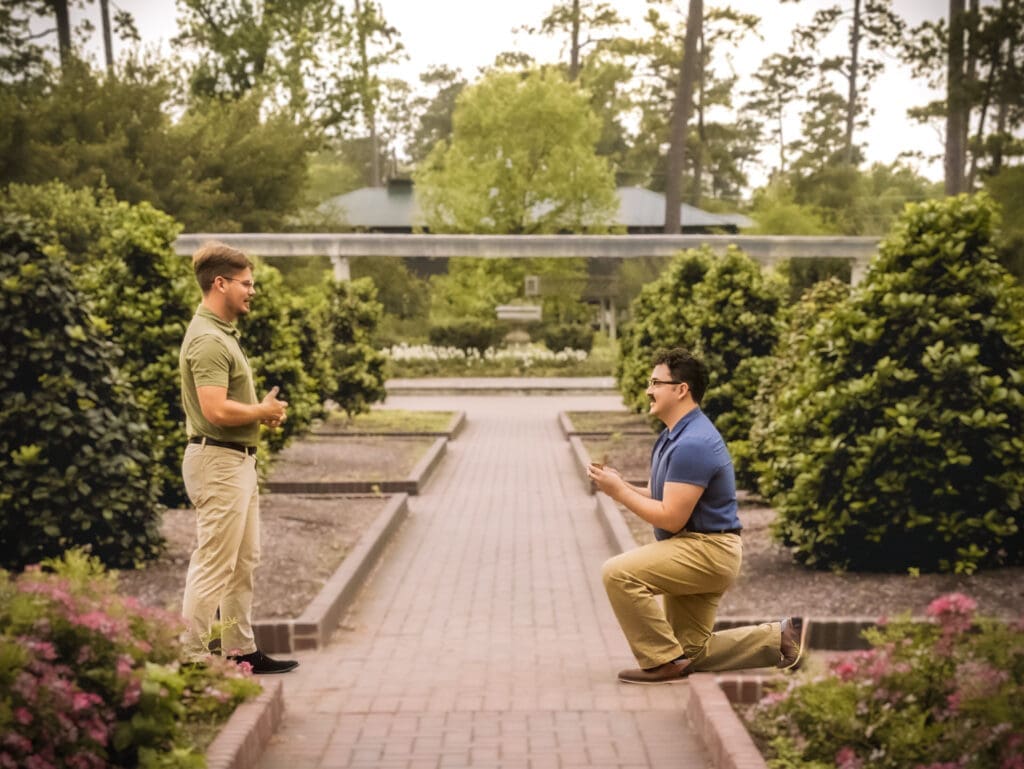 Marriage proposal at Mercer Botanic Gardens near Houston, Texas, with one partner kneeling and presenting an engagement ring in a botanical garden setting.